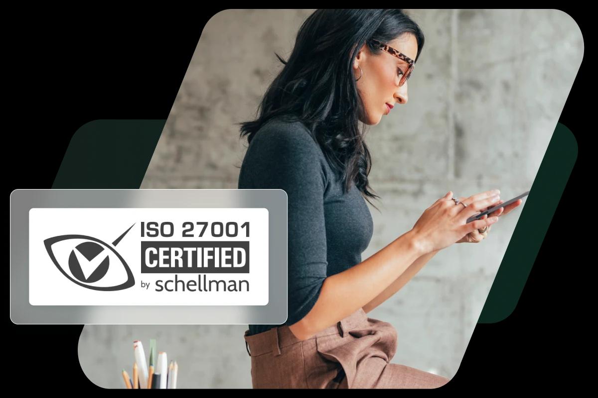 This image shows a woman working in an office overlaid with a badge representing Dashlane’s ISO-27001 certification.