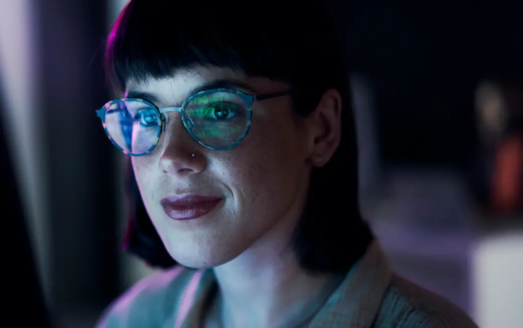 A woman works at her computer, protected as she browses by Dashlane Omnix.