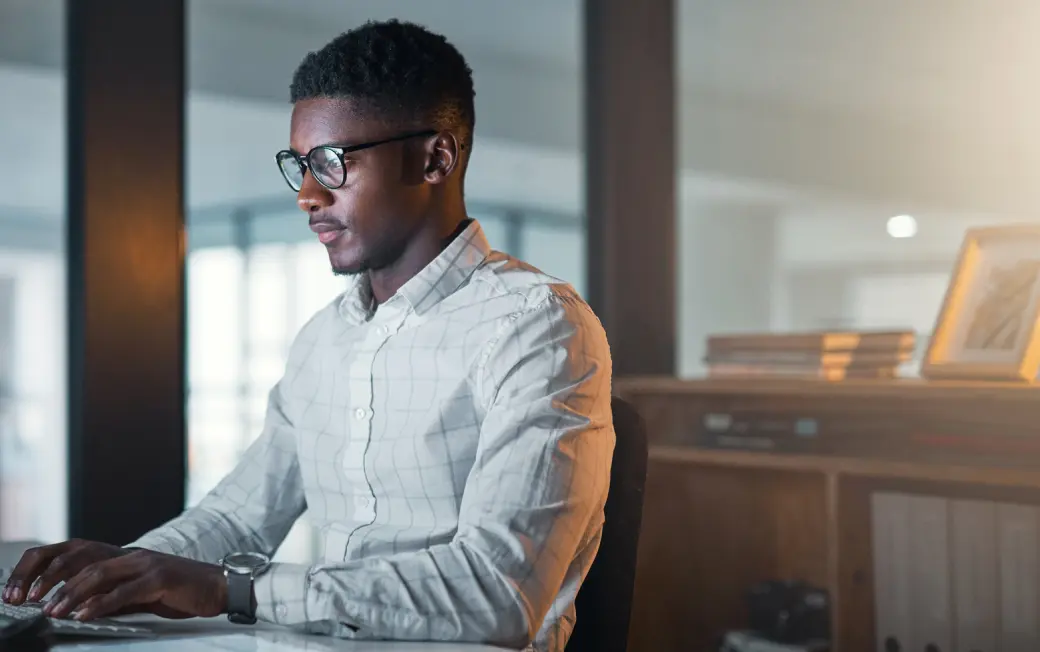 A man works at his computer, protected as he browses by Dashlane Omnix.